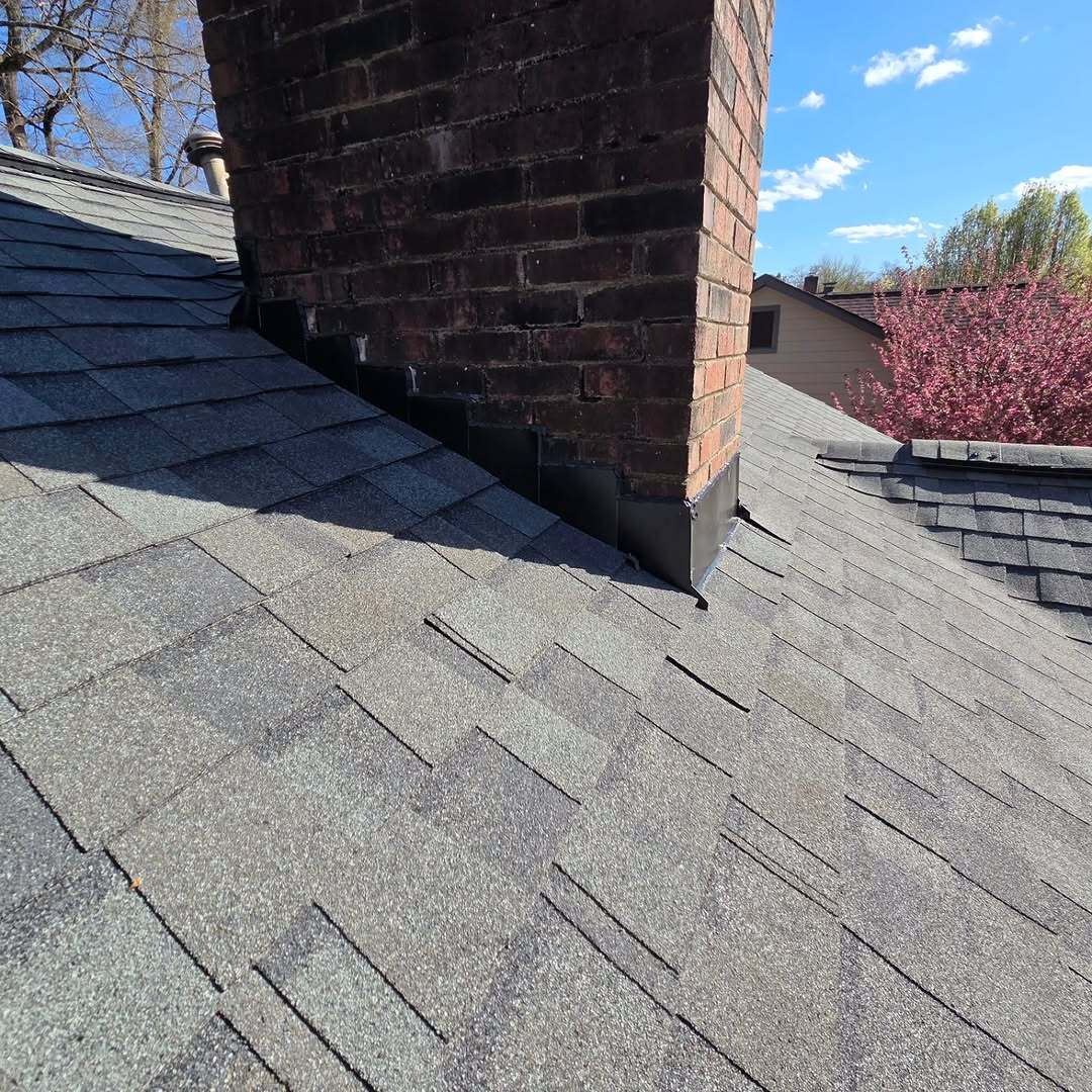 Roof renovation detail around a brick chimney